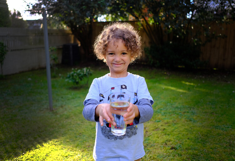 Image of a boy holding a glass filled with top quality drinking water